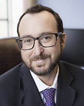 Andrew wearing suit and tie in an office setting.