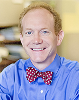 Chris smiling in a blue shirt and red bow tie.