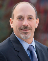 Chris Longo in a dark gray suit and light blue shirt.