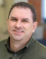 Don wearing a green button down shirt in an office setting.