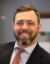 Garrison Beck smiling in a dark gray suit.
