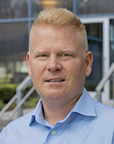 Greg Alban wears a blue collared shirt 