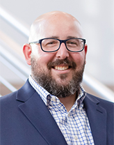 Lou Bekofsky in a blue suit and checkered shirt.