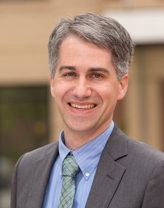 Man wearing gray suit and tie in outdoor setting