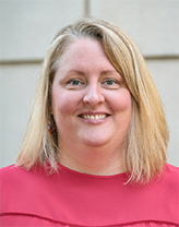 Regan wearing a pink shirt smiling in an outdoor setting