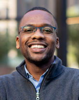 Reggie Askew smiling in a gray sweater.