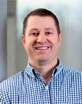 Stephen wearing a checkered shirt in an office setting