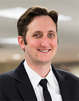 Man wearing a dark suit and tie in an office setting