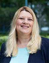 A smiling woman with blonde hair and a blue shirt