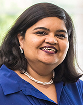 Taruna smiling in a navy blue blouse.