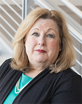 Woman wearing green shirt and black jacket in office setting