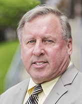 Thomas Donald smiling in a yellow shirt and oatmeal blazer.