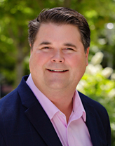 Wayne Robinson in a pink shirt and navy blue jacket.