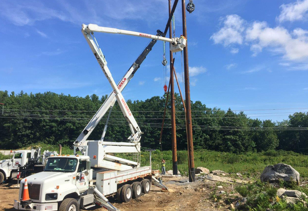 A power truck installs new electric power poles.