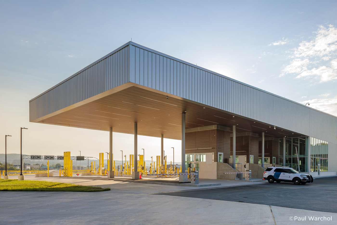 Exterior view of a modern border crossing facility with primary inspection booths and scanning equipment.