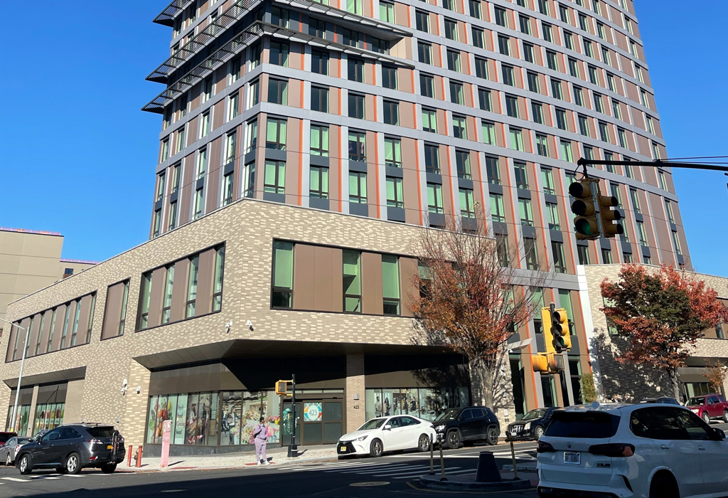 A tall building with many windows located on a downtown street