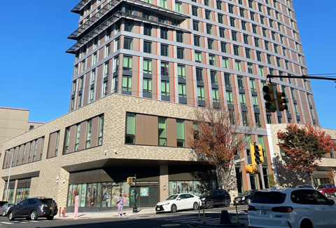 A tall building with many windows located on a downtown street