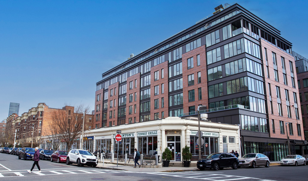 A multistory glass and brick building atop retail space near a playground.