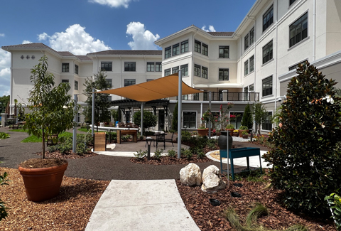 The outside entry flanked with vibrant bushes and small trees.