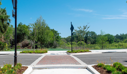 A brick-paved pedestrian crossing located within a park.