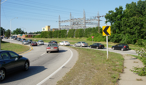 Three lanes of cars merge onto an interstate.