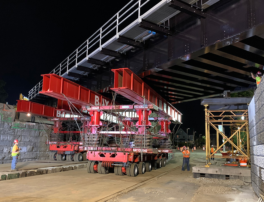 Bridge being moved into place via self-propelled modular transporter.