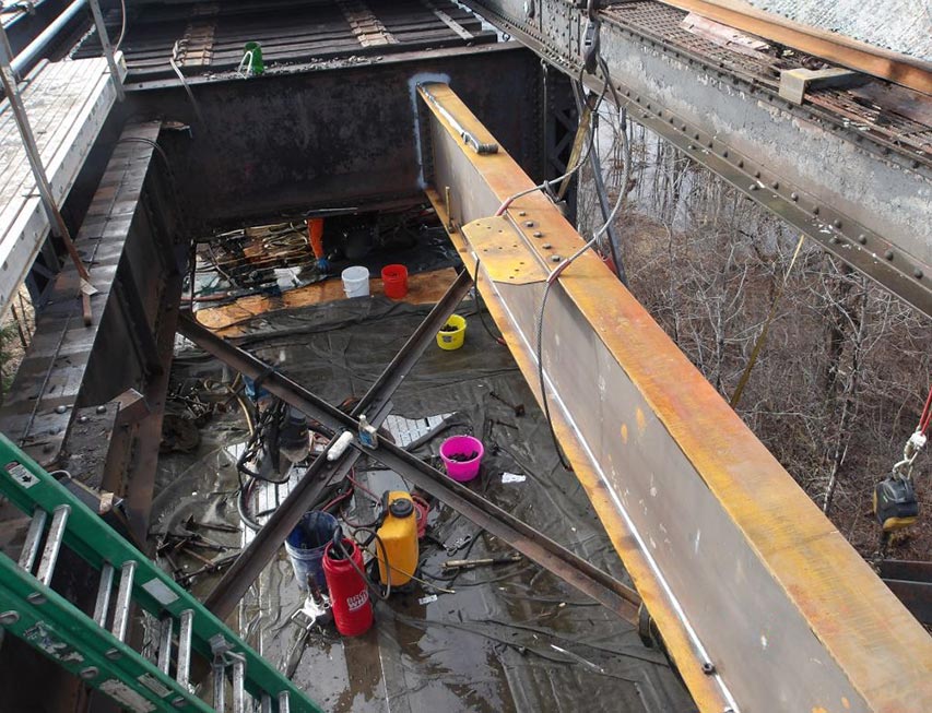 Bridge steel repairs being performed inside a railroad bridge.