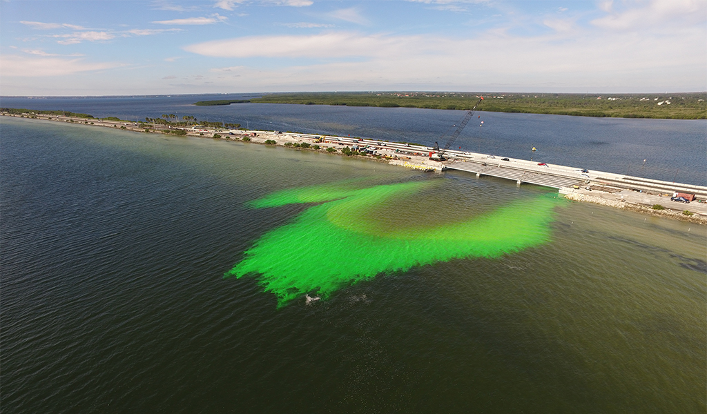 Green dye shows water circulating as it flows under a bridge.