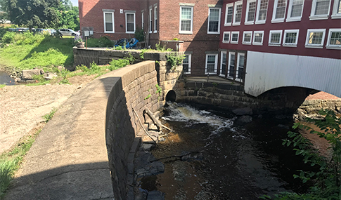 The Upper Sawyer Mill Dam blocks a river from flowing under a building built over a river.