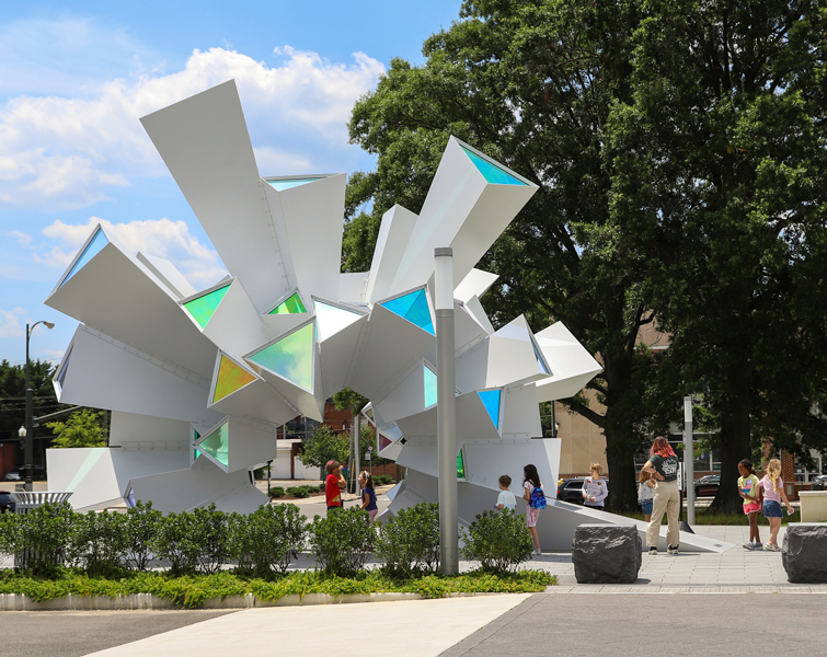 Pathway leading to a kaleidoscopic sculpture in front of a domed science museum building.