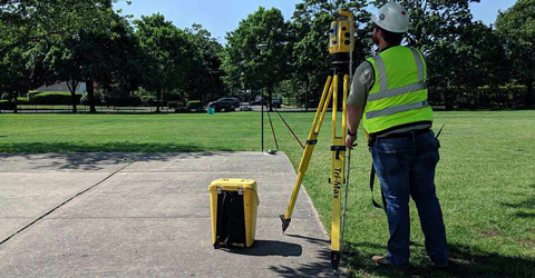 Land surveyor inspecting equipment wearing high visibility vest. 