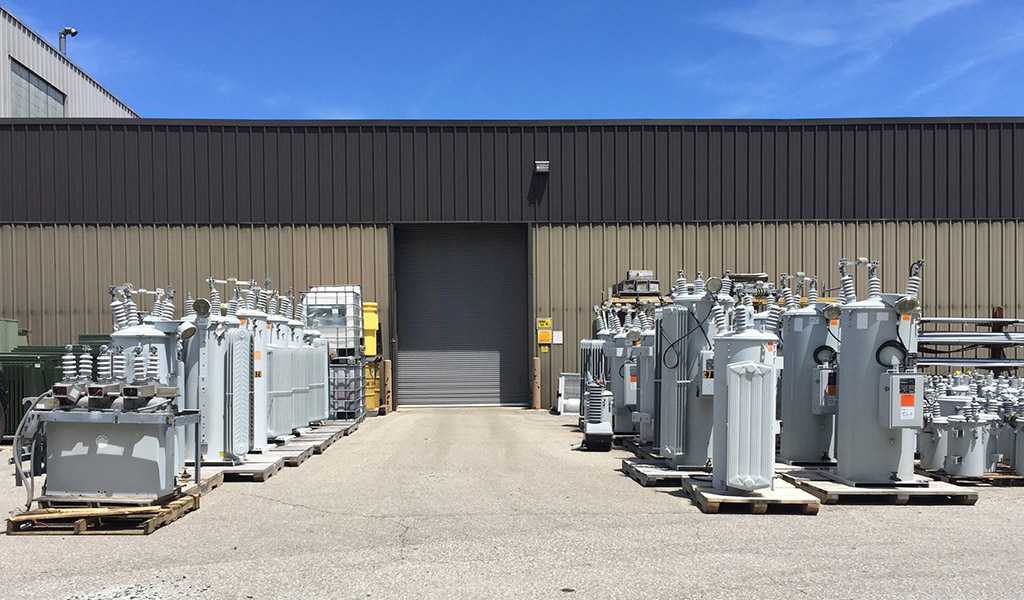 Exterior view of an industrial electrical maintenance facility, with various equipment on wooden pallets.