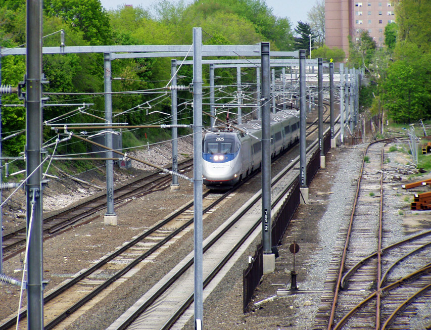 An Amtrak train on tracks under an overhead catenary system.