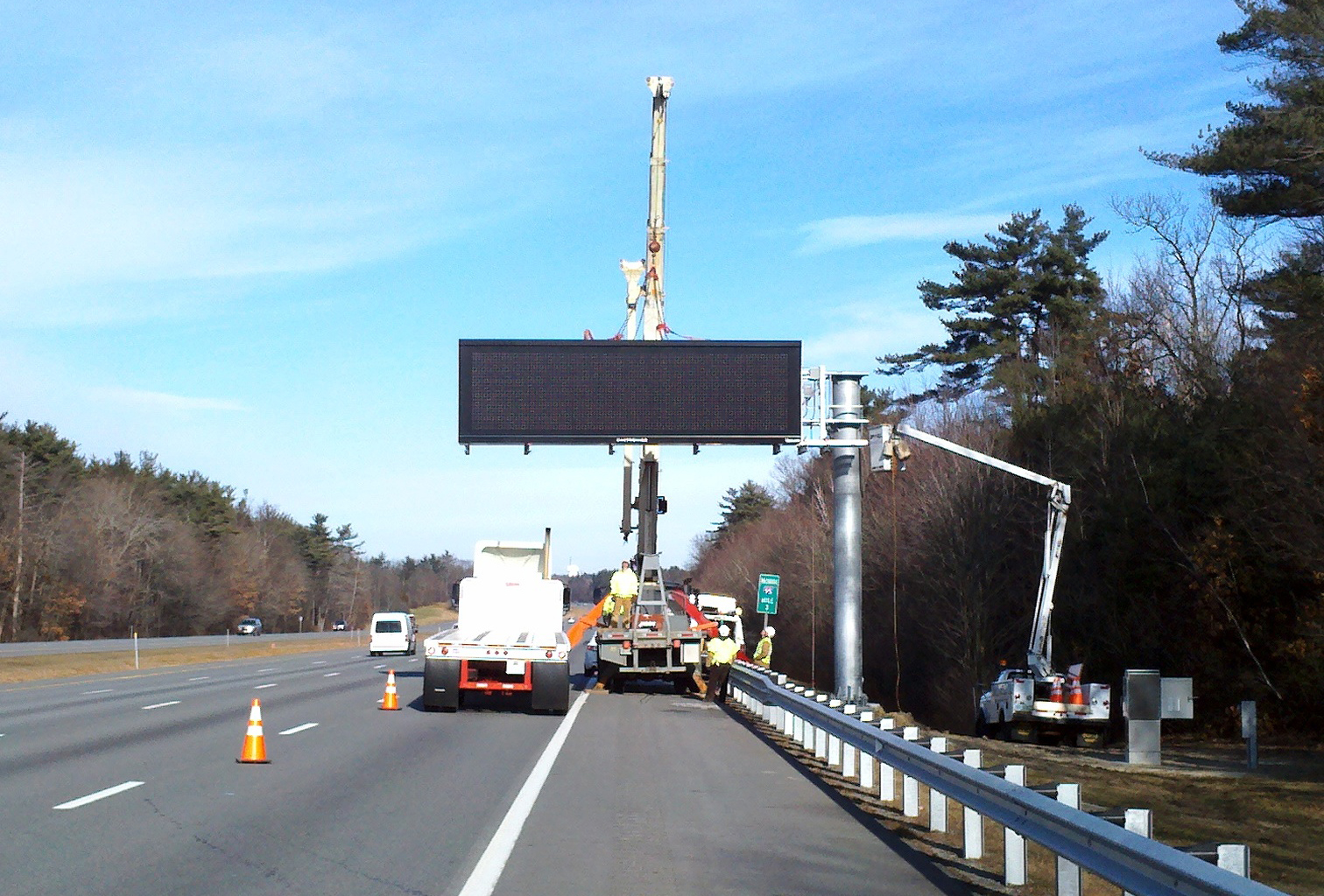 Crew installing an overhead digital messaging sign along highway.