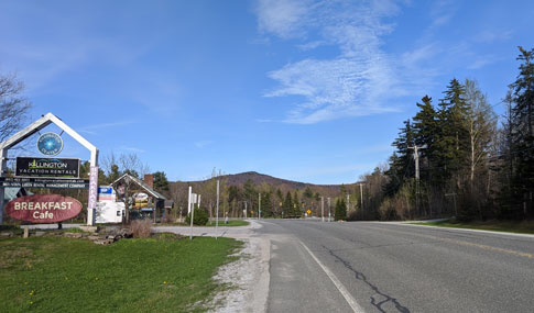 Killington Road, with the ski mountain visible in the background and signs for businesses on the left.