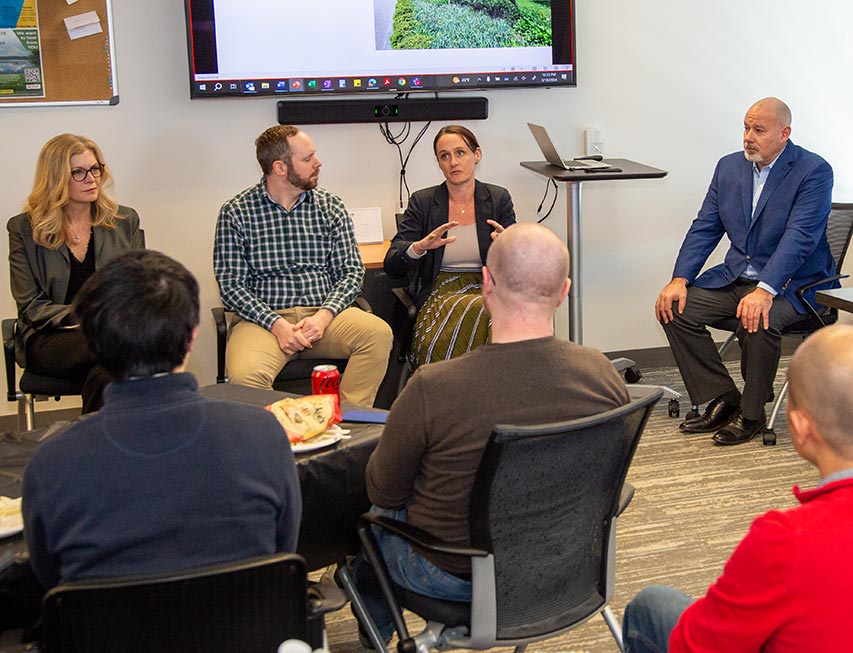 A group of VHB team members gather in a conference room while a sustainability presentation is projected.