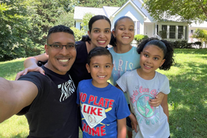 VHB team member and family pose for a photo in front of a house