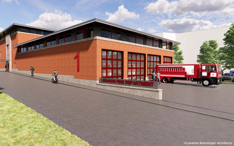 Exterior view of the Lebanon Fire Department building with a fire truck parked outside, featuring red brick construction and large red garage doors. 