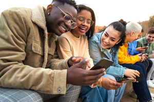 college students having fun using mobile phone together in campus outdoor