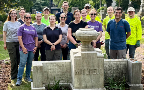 A group of VHB employees stand around a cemetery headstone.