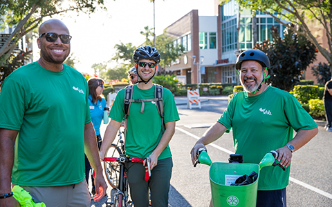 Three VHB team members in green shirts standing by bicycles