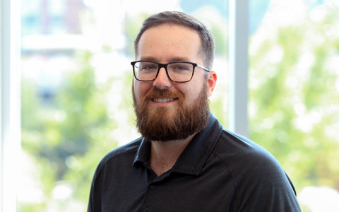 Dan Gleason smiles at the camera wearing a black polo shirt.  