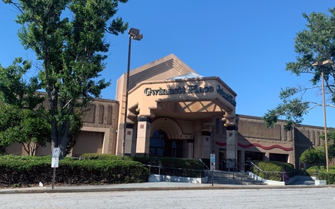 The entrance to a suburban shopping mall bordered by two trees and vegetative plantings. 