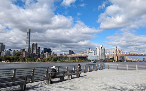 View of East River with people sitting on benches. 