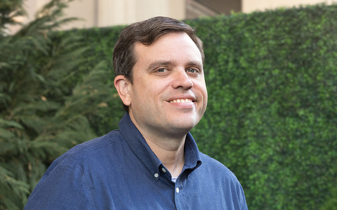 John McSweeney wears a blue button-down while outside.