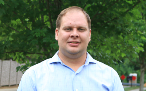 Kevin Westra smiles at the camera outside wearing a blue shirt