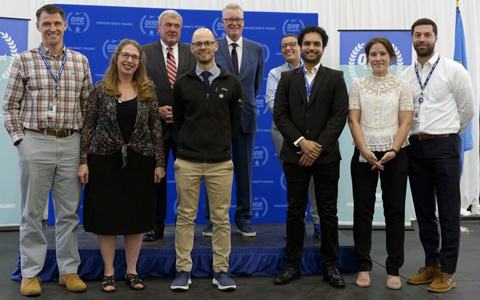 Nine VHB and Massport team members stand together on stage at the One Massport Business Meeting to accept the Outstanding Achievement Award.  