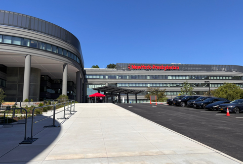 A hospital building with cars parked in front of it.