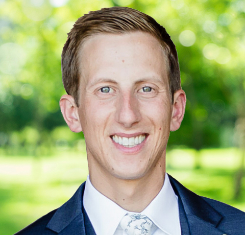 Pete Doster smiles at the camera wearing a blue blazer and tie.