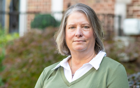 Stephanie Roberts stands outside a building wearing a green sweater.